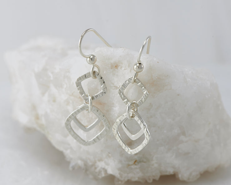Silver hammered squares earrings on white rock
