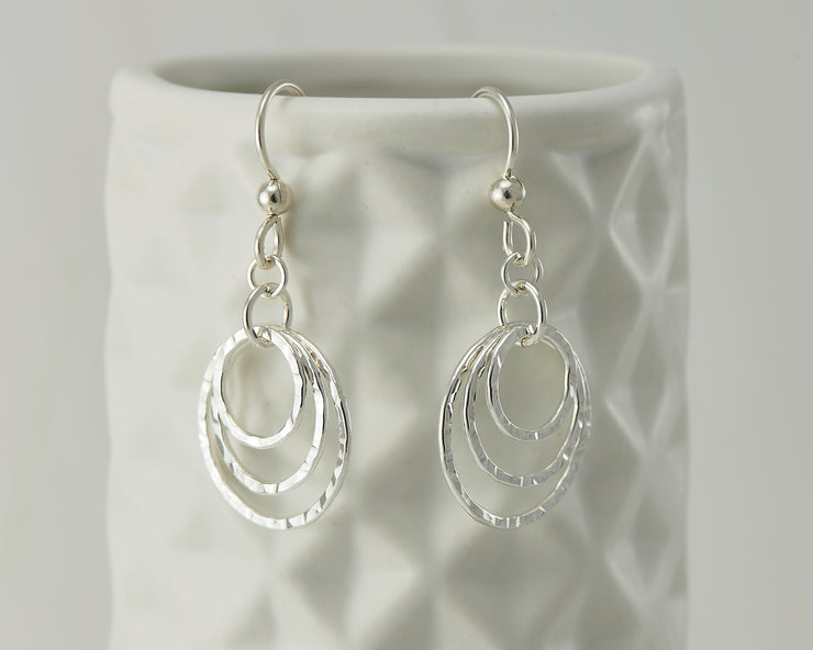 Silver hammered hoop earrings on geometric vase