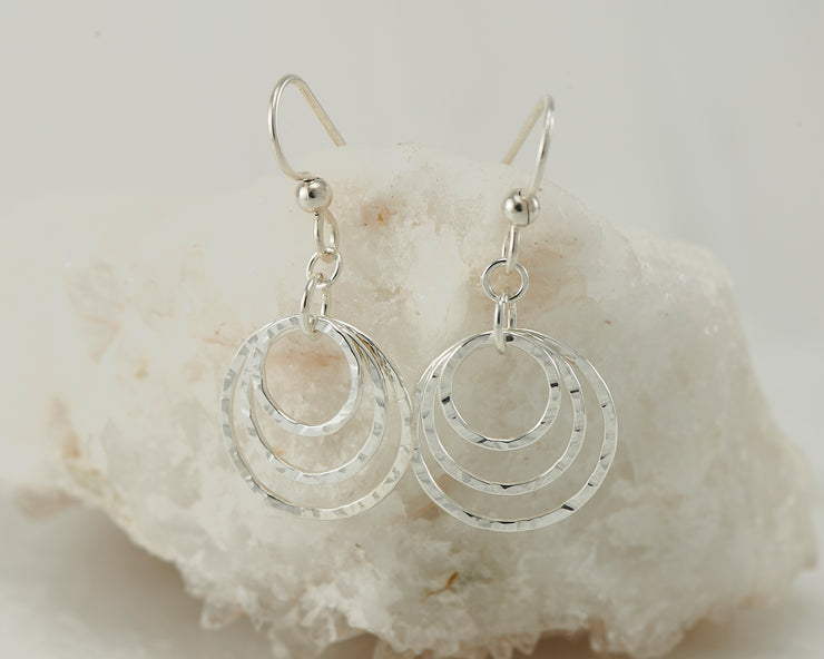 Silver hammered hoop earrings on white rock