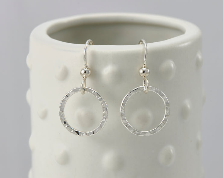 silver hammered hoop earrings on geometric vase