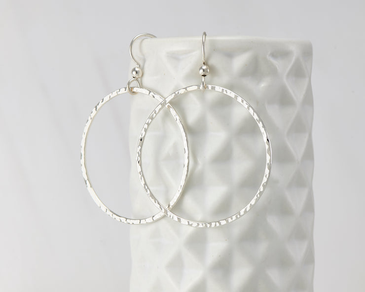 Silver large hammered hoop earrings on geometric vase
