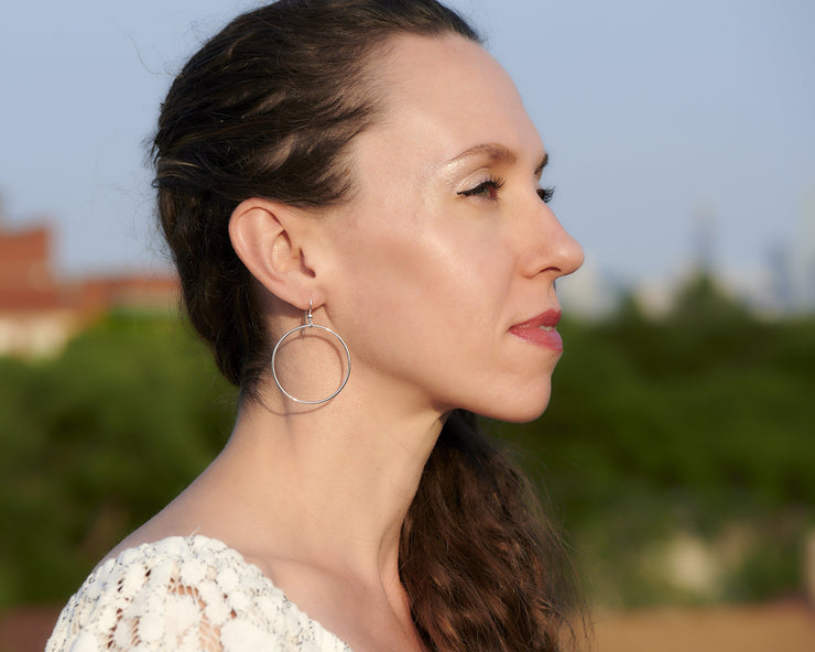 Woman wearing silver large hammered hoop earrings