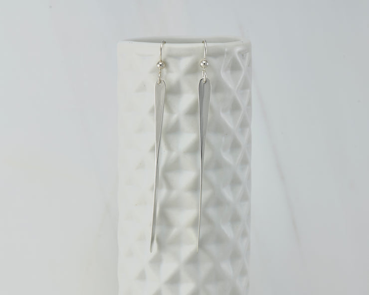 long silver bar earrings on geometric vase