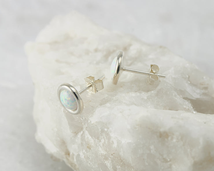 Silver opal stud earrings on white rock