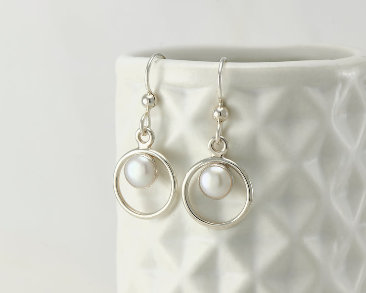 Silver pearl hoop earrings on geometric vase