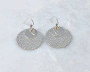 Silver polished hammered discs earrings on white marble