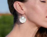 close up of woman wearing silver hammered discs earrings