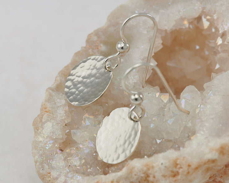 Small silver earrings on a piece of gypsum