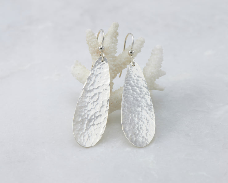 silver hammered teardrop earrings on coral