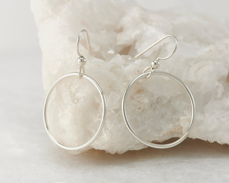 Silver medium hoop earrings on white rock