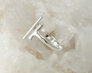 Silver parallel bars ring on white rock