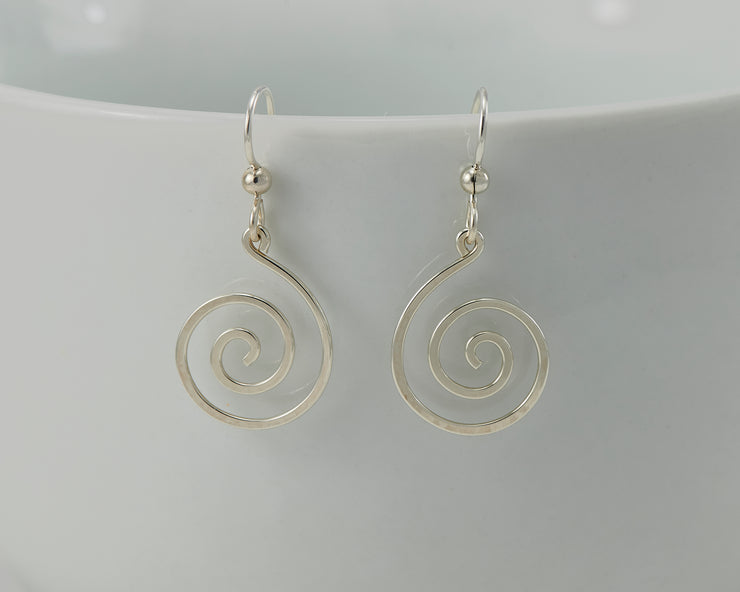 silver spiral earrings on white cup