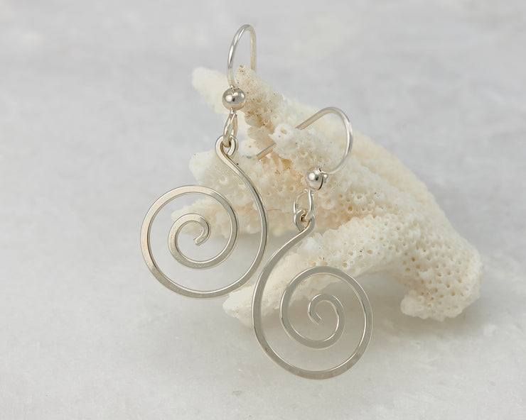 silver spiral earrings on coral