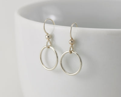 silver small hoop earrings on white cup