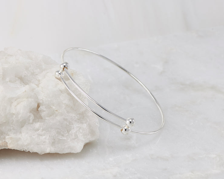Silver adjustable bangle bracelet on white rock