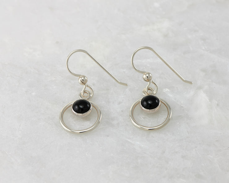 Silver polished black onyx earrings on white marble