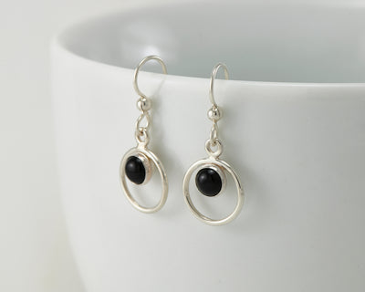 Silver black onyx earrings on white cup