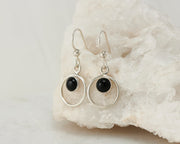 Silver black onyx hoop earrings on white rock