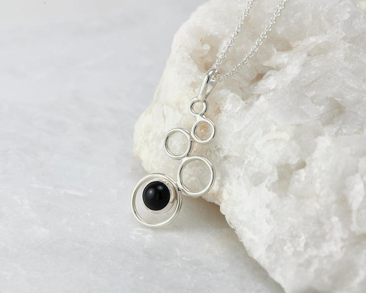 Silver black onyx pendant leaning on white rock