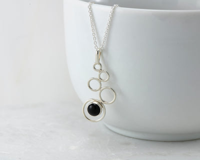 silver black onyx pendant necklace hanging from white cup
