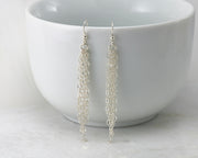 Silver chandelier earrings on white cup