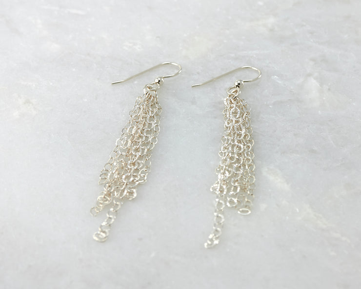 Silver chandelier earrings on white marble