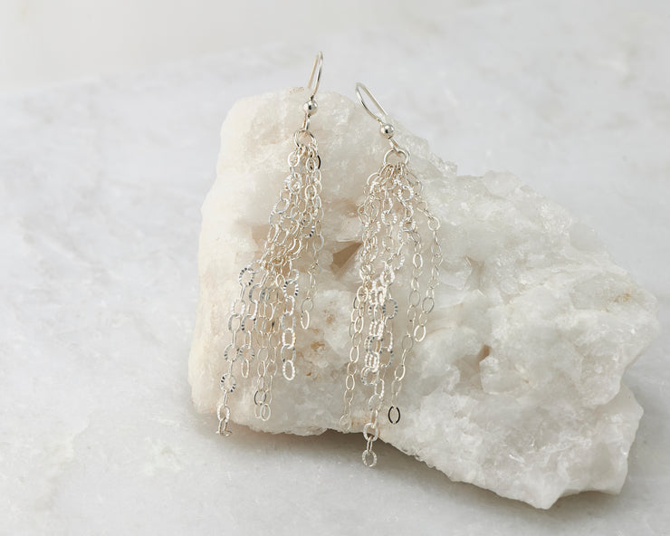 Silver chandelier earrings on white rock