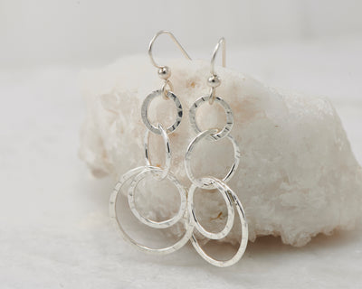 Silver hammered circles earrings on white rock