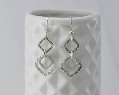 Silver hammered squares earrings on geometric vase