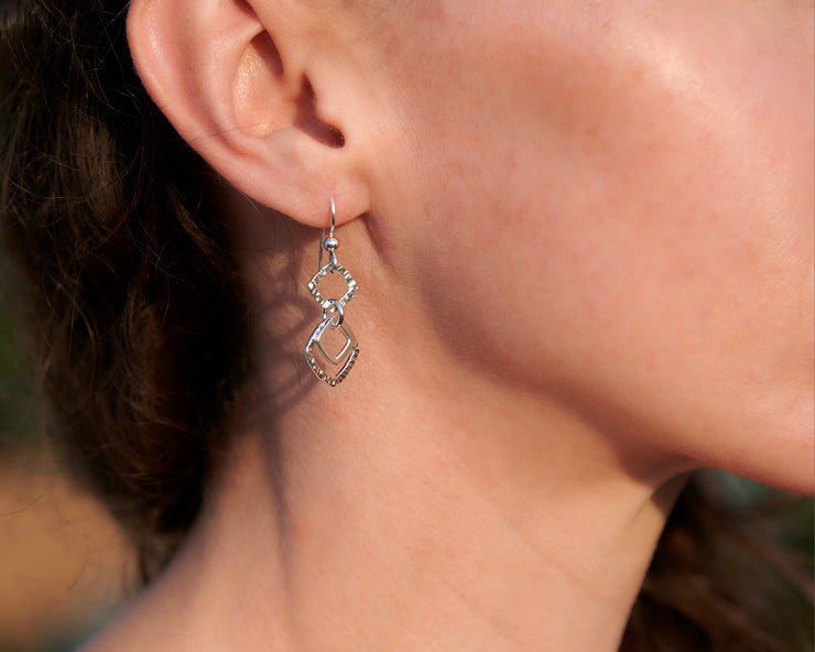 close-up of woman wearing silver hammered squares earrings