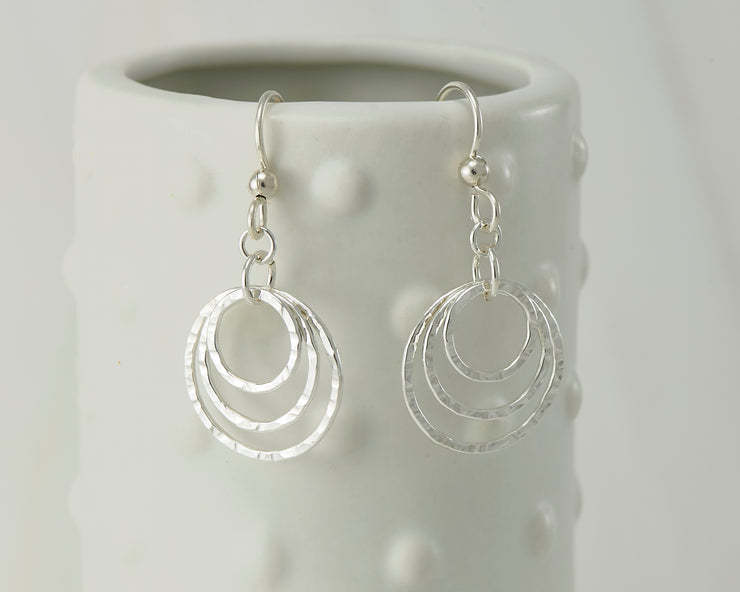 Silver polished hammered hoop earrings on dotted vase