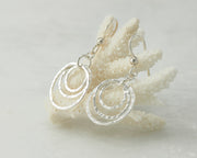 Silver hammered hoop earrings on coral