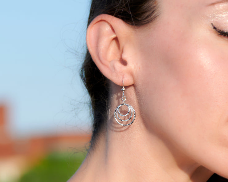 close up of woman wearing silver hammered hoop earrings