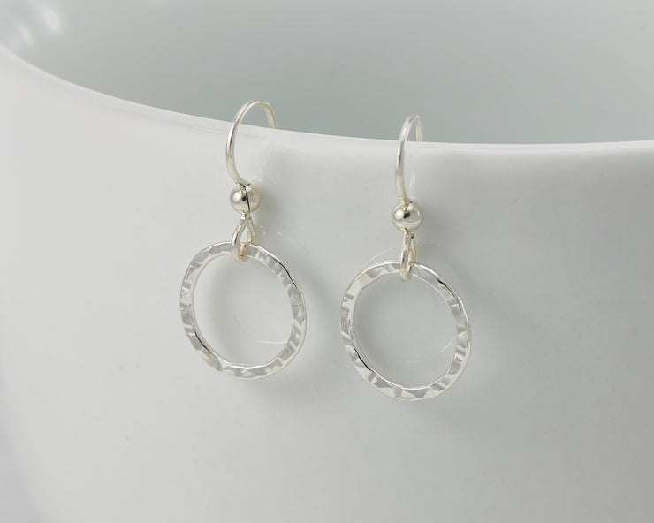 silver hammered hoop earrings on white cup