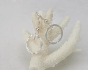 silver hammered hoop earrings on coral