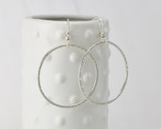 Silver large hammered hoop earrings on dotted vase