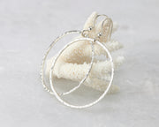 Silver large hammered hoop earrings on coral