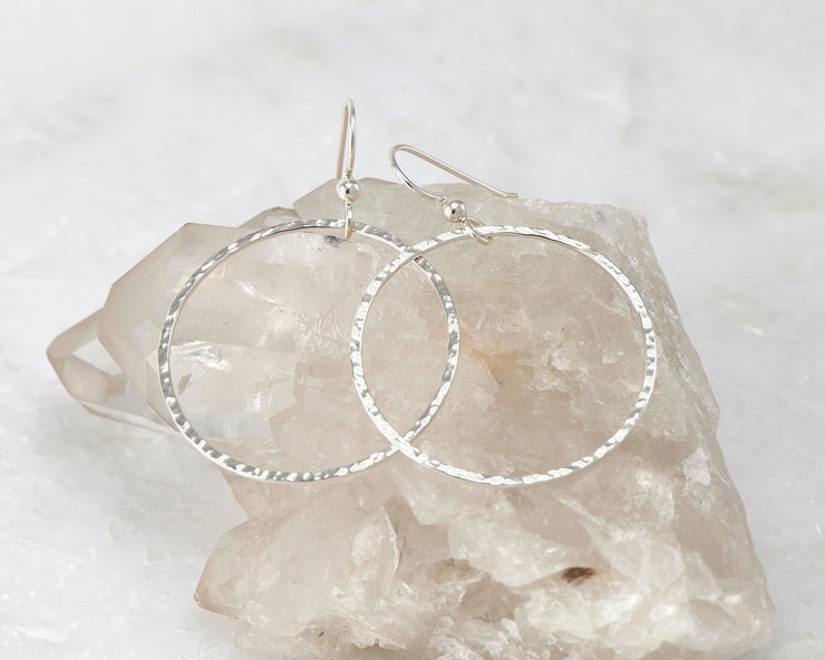 Silver large hammered hoop earrings on crystal rock
