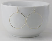 silver large hoop earrings on white cup