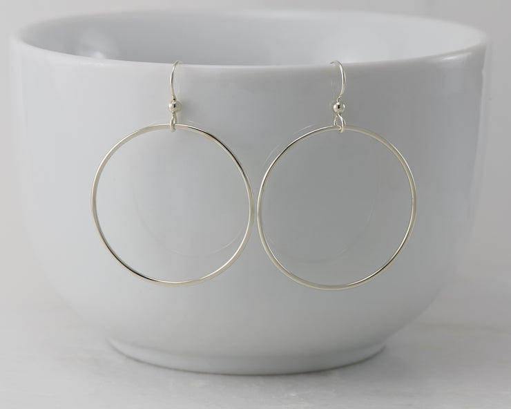 silver large hoop earrings on white cup