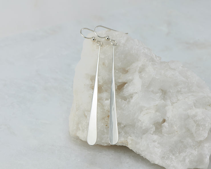 long Silver dangle bar earrings on white rock