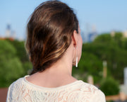 woman wearing facing away long silver bar earrings