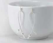 Silver long curved earrings on white cup