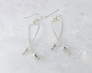 Silver long curved earrings on white marble