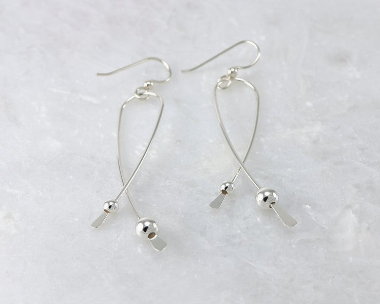 Silver long curved earrings on white marble