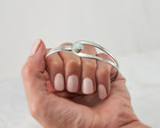 woman holding silver bracelet with opal