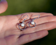 Woman holding silver hoop opal earrings