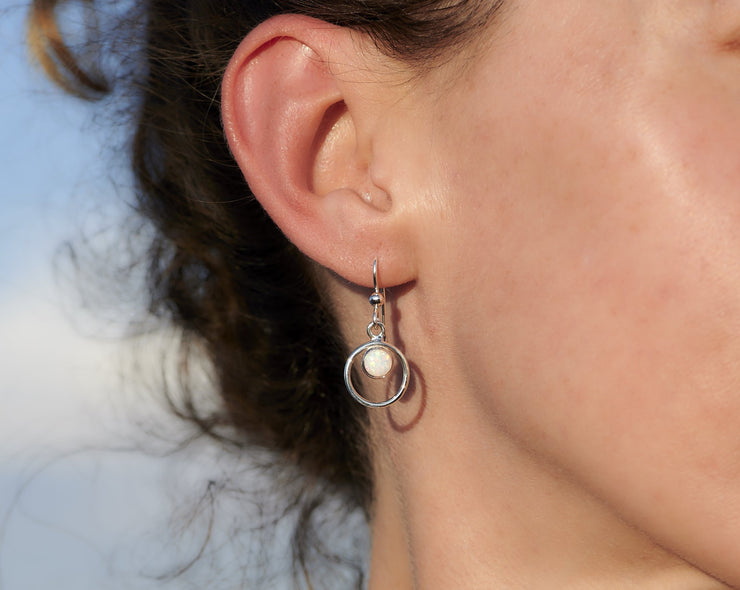 Woman wearing silver hoop opal earrings