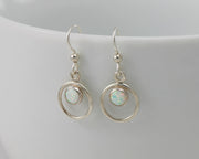 Silver opal earrings on white cup