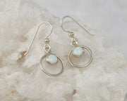Silver opal hoop earrings on white rock